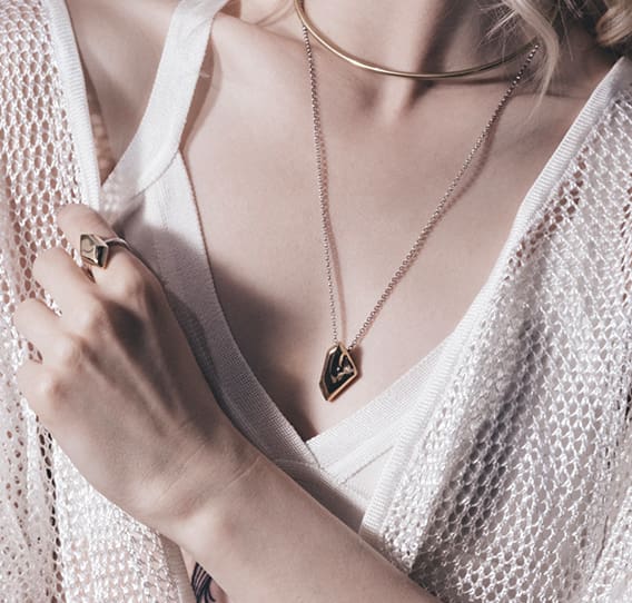 A woman wearing two necklaces and one is holding her hand