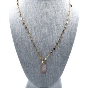 A necklace that is on display in front of a gray background.