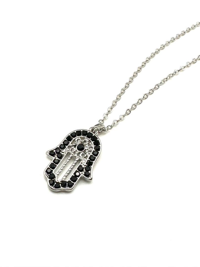 A silver necklace with a hamsa hand on it.