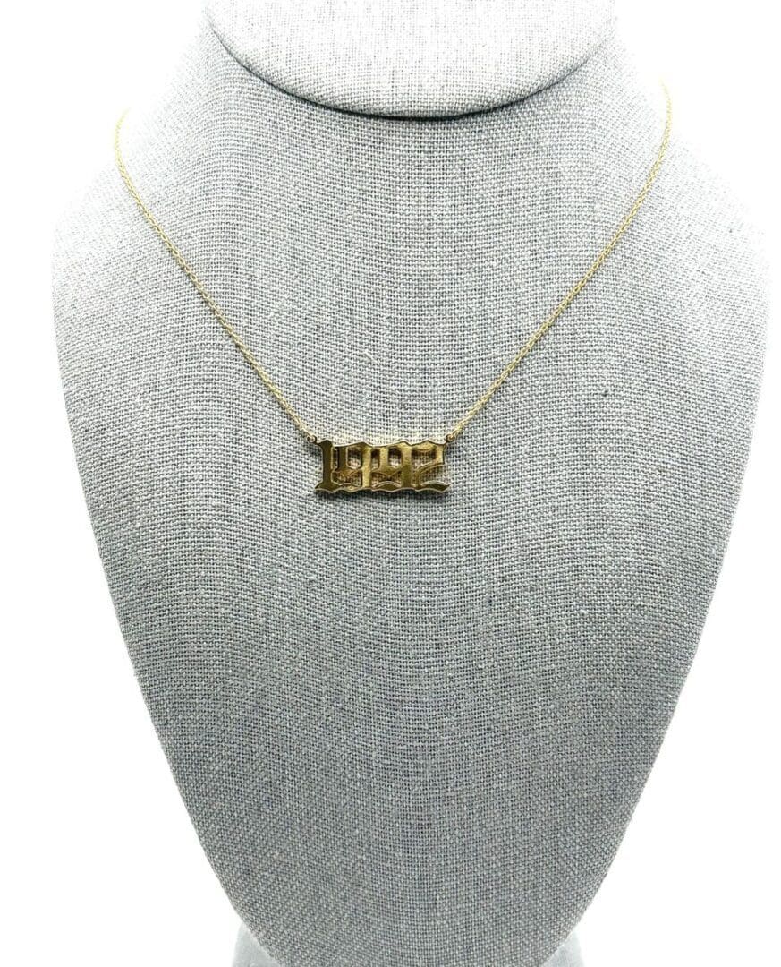 A gold necklace with the word " team " on it.