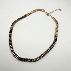 A necklace that is made of black and gold beads.