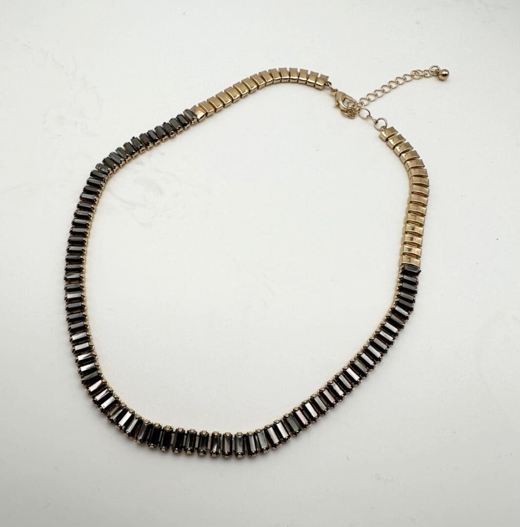 A necklace that is made of black and gold beads.